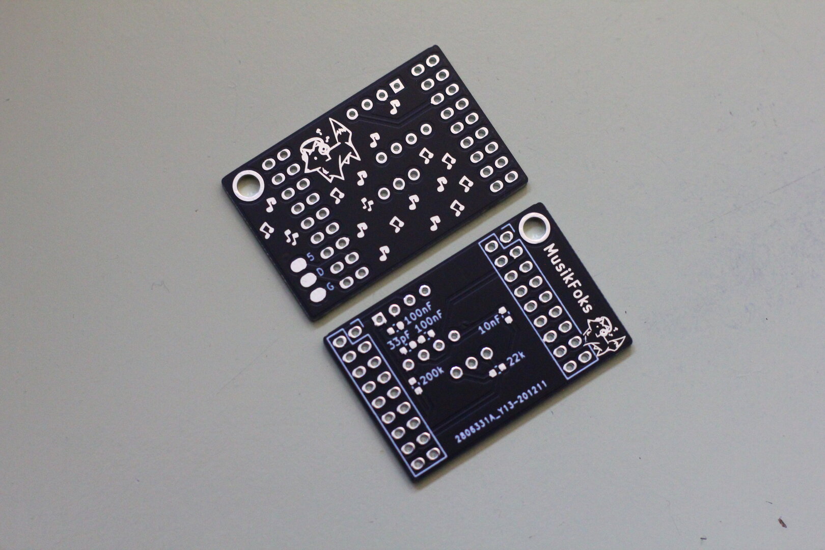 Two rectangular PCB's, decorated with a foks listening to headphones, with music notes sprawled around