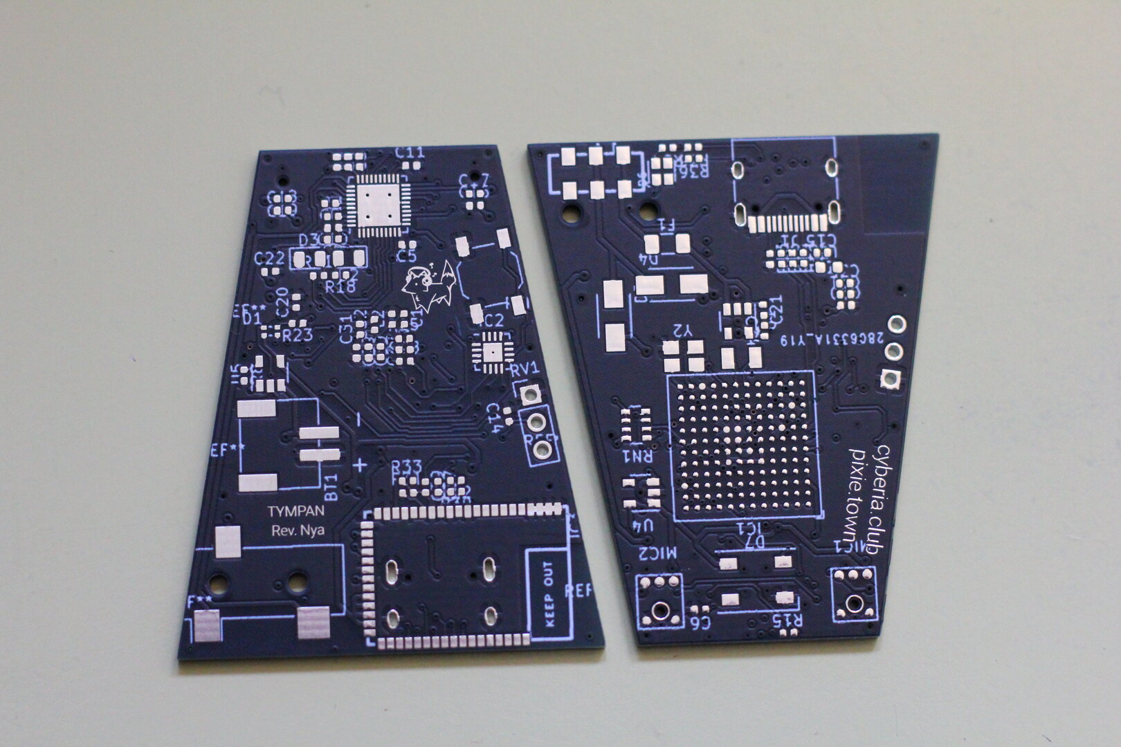 Two trapezoid shaped PCB's, showing the front and back design of the hearing aid PCB